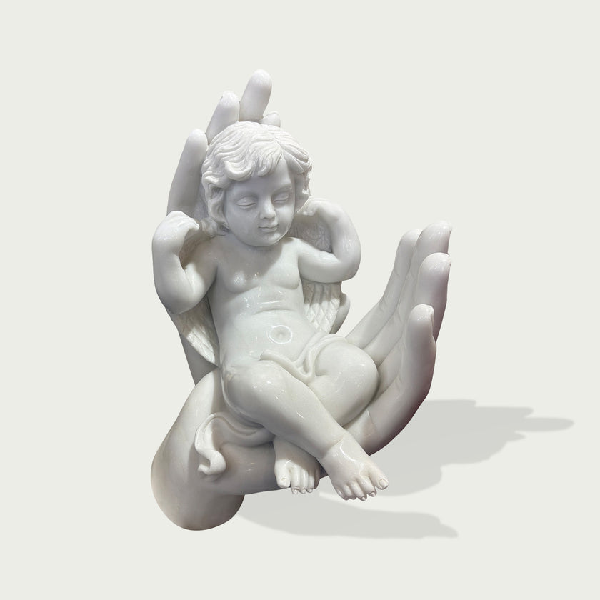 Sleeping Angel In Hands Natural Marble Statue on a hand against a light gray background