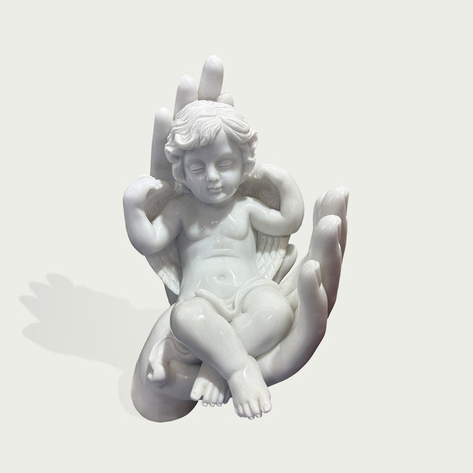 Sleeping Angel In Hands Natural Marble Statue on a hand against a light gray background