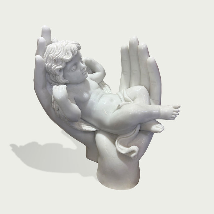 Sleeping Angel In Hands Natural Marble Statue on a hand against a light gray background