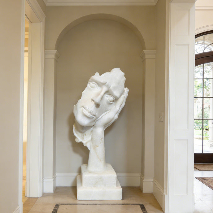 Fragmented Face Marble Sculpture in a hallway with neutral walls and flooring.