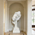 Fragmented Face Marble Sculpture in a hallway with neutral walls and flooring.
