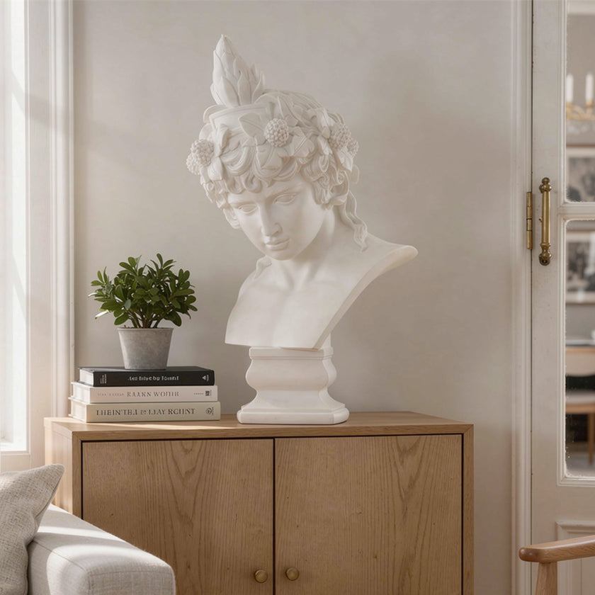 Classic Male Greek Statues Marble Bust Sculpture on a wooden cabinet with books and a plant in a bright room.