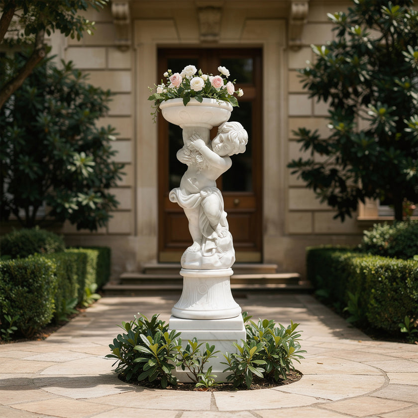 White marble cherub planter statue filled with flowers, displayed at a luxury villa entrance with hedges and classic garden pathway.