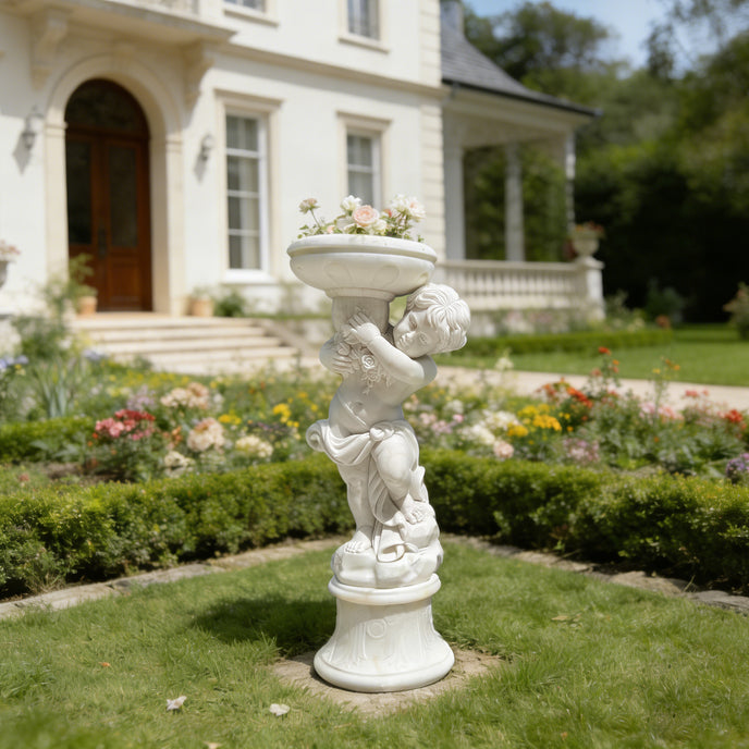 Natural white marble cherub flower planter statue placed in a villa garden with lawn, colorful flowers, and elegant home background.