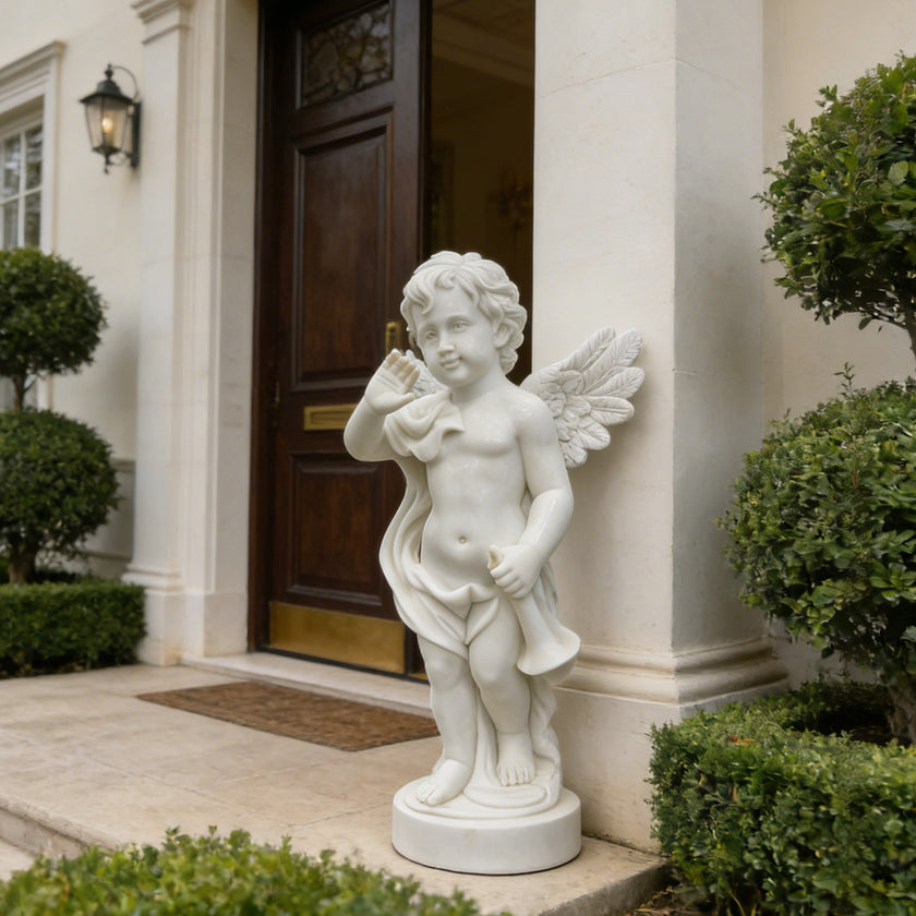White marble cherub angel statue displayed beside a villa entrance, with detailed wings, waving pose, and classical outdoor charm.