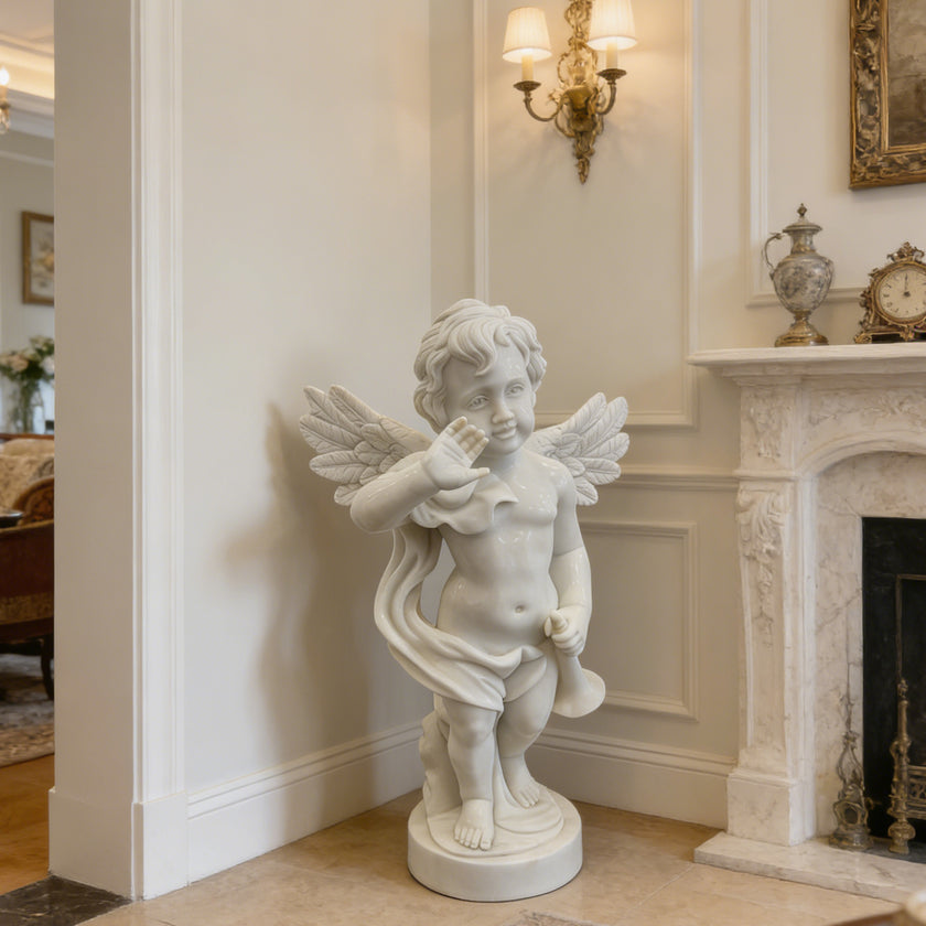 Natural white marble cherub angel statue placed indoors near a fireplace, adding a soft classical accent to elegant home decor.