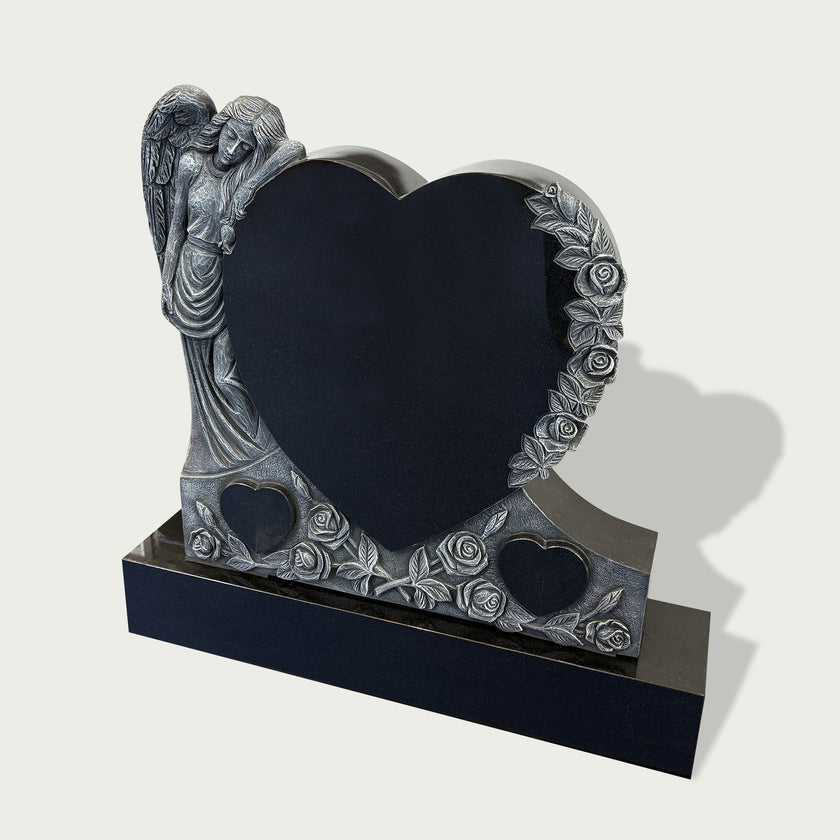 Guardian angel heart headstone with floral rose carvings, black granite heart panel, silver-toned angel figure, and elegant memorial base design.