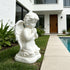 White marble praying angel statue displayed beside a modern pool garden, with folded hands, soft wings, and peaceful kneeling pose.