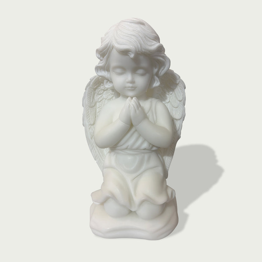 Close view of natural white marble praying angel figure with gentle face, folded hands, soft curls, and layered feather wings.