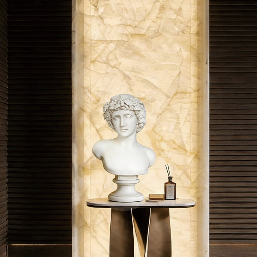 White marble male bust displayed on an indoor console table, adding classical sculpture charm to a luxury interior with warm marble wall lighting.