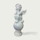 A white classical-style cherub statue seated on a round pedestal, photographed against a plain light gray background with a soft shadow.