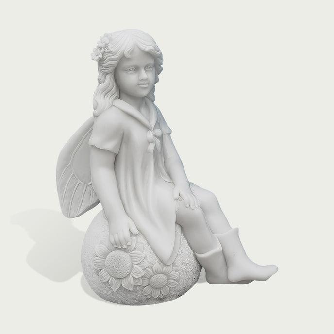 A white stone or resin figurine of a winged girl sitting on a sunflower-covered sphere, shown against a plain light gray background.