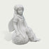 A white stone or resin figurine of a winged girl sitting on a sunflower-covered sphere, shown against a plain light gray background.