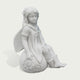 A white stone or resin figurine of a winged girl sitting on a sunflower-covered sphere, shown against a plain light gray background.