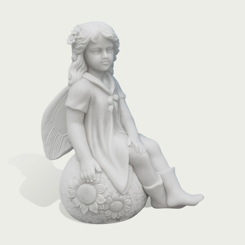 A white stone or resin figurine of a winged girl sitting on a sunflower-covered sphere, shown against a plain light gray background.
