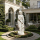 A white classical-style female statue stands in a landscaped garden courtyard in front of a large cream-colored house with arched windows and patio seating.