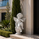 White marble cherub garden statue displayed near a modern entrance with elegant landscaping and timeless angelic design
