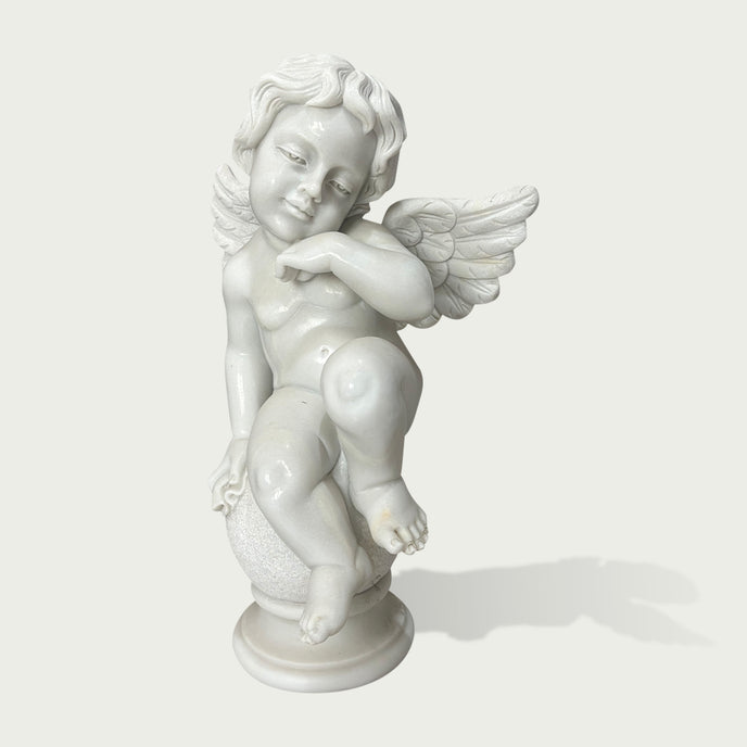 White marble cherub angel statue sitting on a decorative sphere with carved wings and detailed classical sculpture design