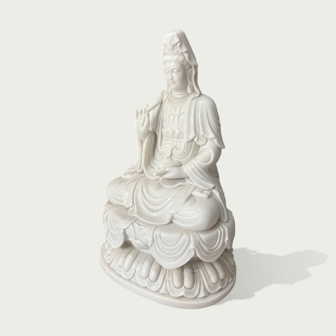 Side view of a white marble Guanyin sculpture showing detailed flowing robes, lotus base, and handcrafted stone carving craftsmanship