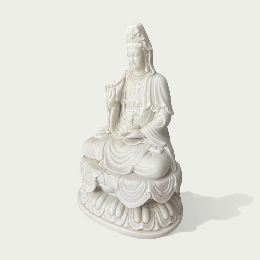 Side view of a white marble Guanyin sculpture showing detailed flowing robes, lotus base, and handcrafted stone carving craftsmanship
