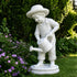 White marble gardener boy statue with watering can displayed among flowers and greenery, elegant outdoor garden sculpture.