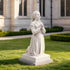 White marble praying girl statue displayed in a garden setting, featuring elegant carved details, flowing robes, and peaceful devotional design.