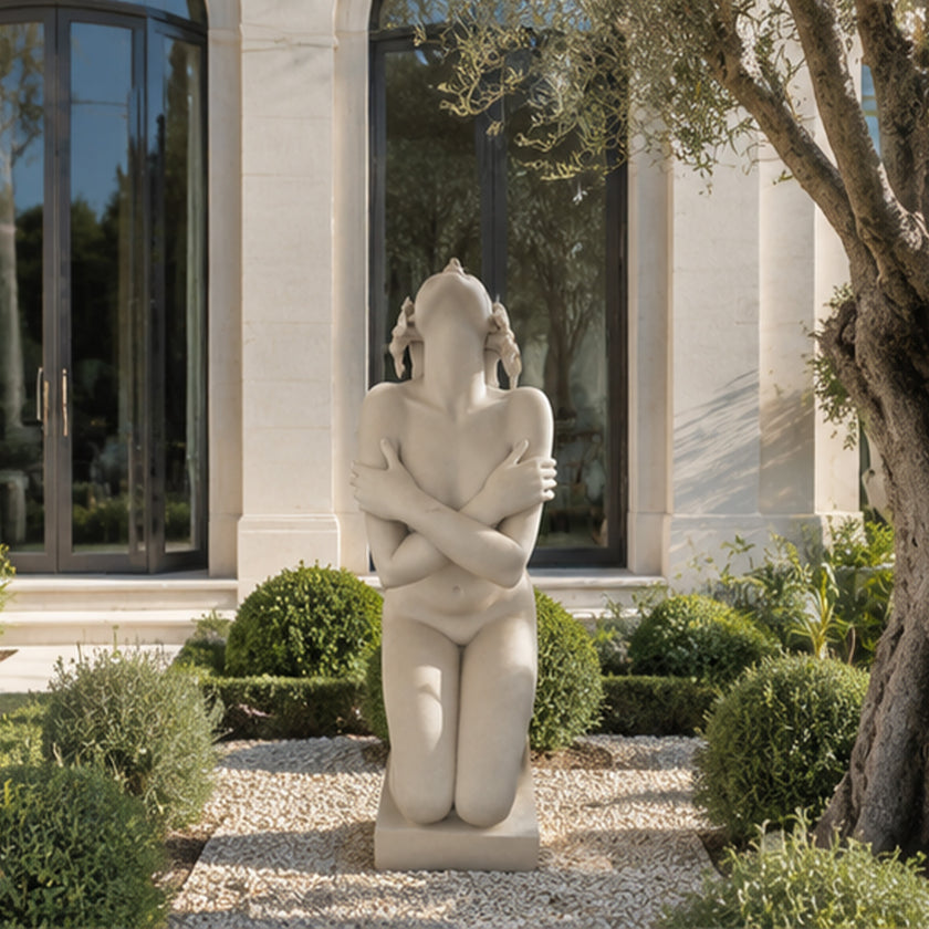 White marble kneeling female statue displayed outdoors with modern architecture and refined classical sculpture design