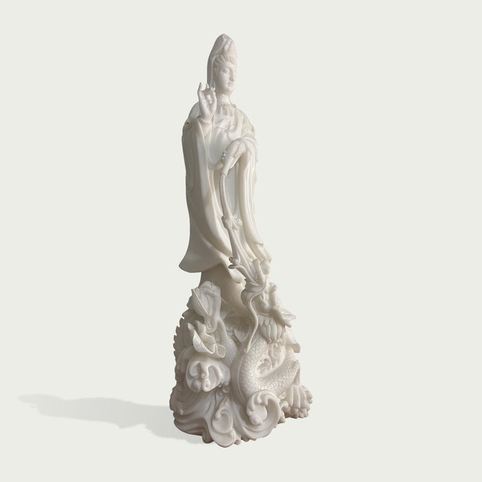 Side view of a white marble Guanyin sculpture featuring delicate robe folds, graceful posture and detailed dragon pedestal design with traditional craftsmanship