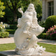 White marble smiling Buddha statue riding a fish with flowing water wave details, carved stone garden sculpture symbolizing prosperity, fortune, and good luck.