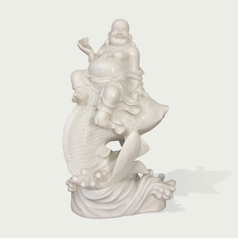 Front view of a white marble Laughing Buddha riding a fish sculpture, featuring detailed scales, flowing robes, and elegant carving for feng shui garden decor.
