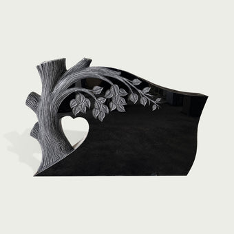 Black marble memorial marker featuring a carved Tree of Life design with detailed branches, leaves, heart opening, and smooth polished granite finish.