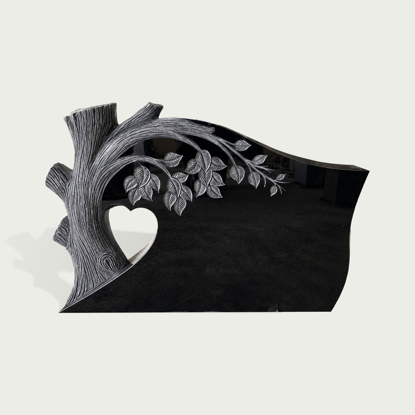 Black marble memorial marker featuring a carved Tree of Life design with detailed branches, leaves, heart opening, and smooth polished granite finish.