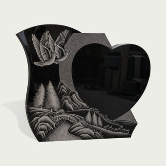 Polished black granite heart memorial marker featuring carved white doves, forest scenery, mountains, and river landscape design for a meaningful grave monument.