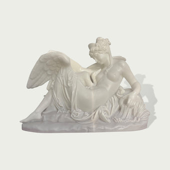 White marble sculpture of a reclining angel figure with large wings, flowing fabric, and classical carved details