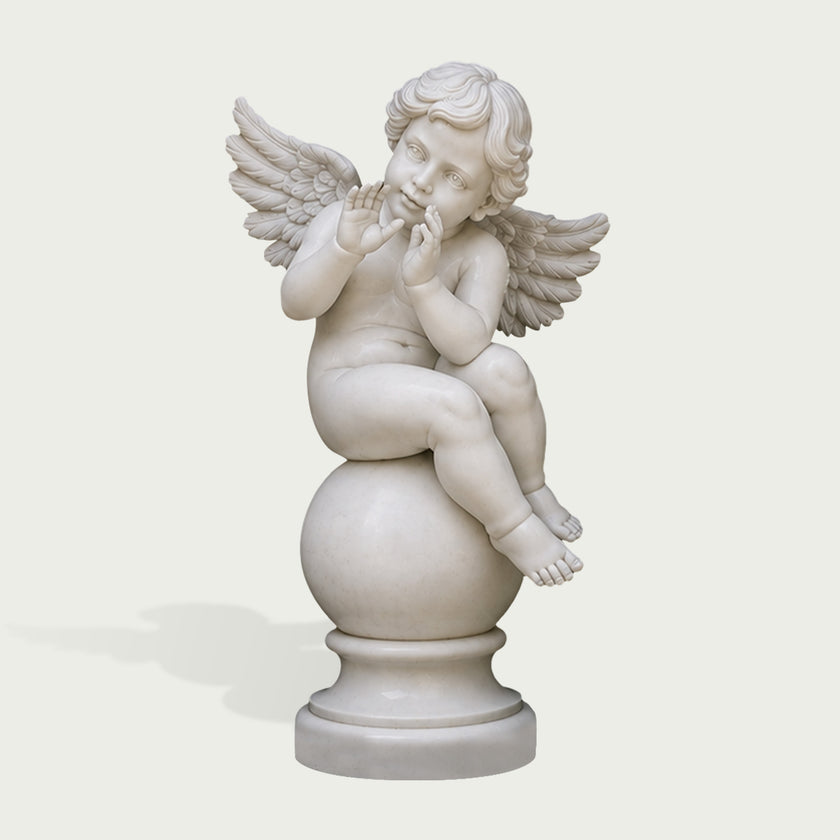A white marble cherub figurine sitting on a round pedestal, with small wings and a thoughtful expression, photographed against a light gray background.