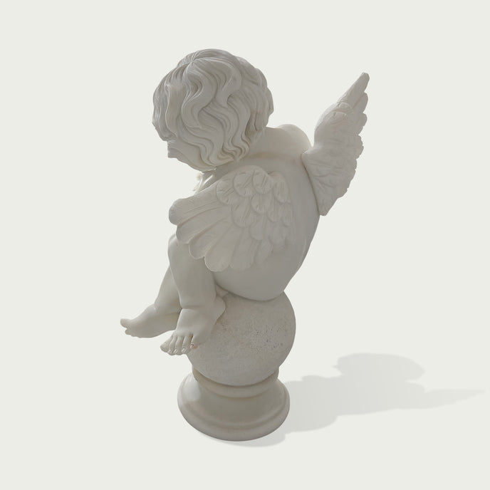 A white marble-style cherub statue shown from the back, seated on a round pedestal against a light gray background.