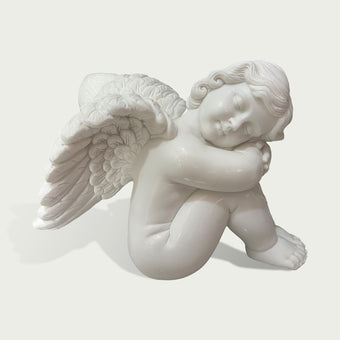 Close view of a white marble angel cherub sculpture with smooth carved details, feathered wings and tranquil sleeping design.