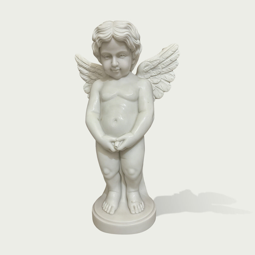 White marble winged cherub statue standing on a round base, featuring carved feather wings, curly hair, childlike figure, and classical angel sculpture details.