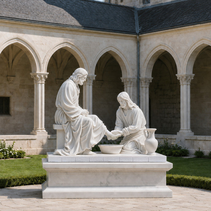 White marble Jesus washing feet sculpture displayed in a monastery courtyard, featuring two biblical figures with carved robes, basin and classical religious details.