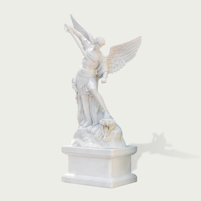 Three-quarter view of a polished white marble Archangel Michael sculpture standing on pedestal with detailed wings, robe folds and carved dragon figure.