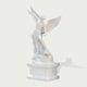 Three-quarter view of a polished white marble Archangel Michael sculpture standing on pedestal with detailed wings, robe folds and carved dragon figure.