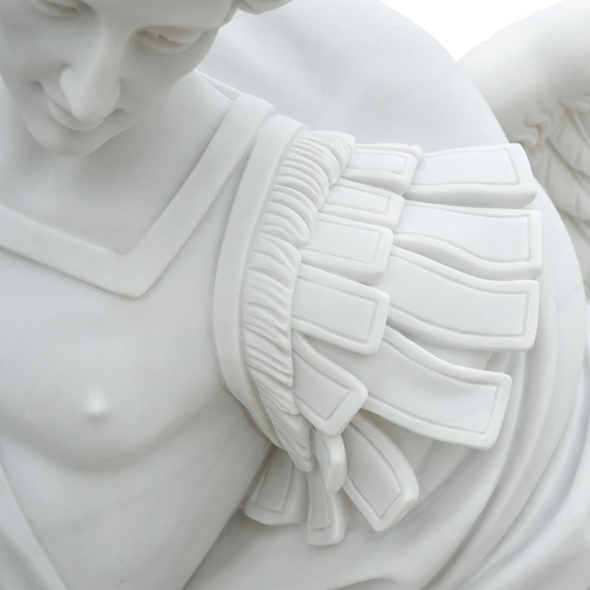 Close-up detail of white marble Archangel Michael sculpture showing finely carved wings, armor details and smooth polished stone craftsmanship.