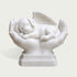 White marble pet memorial sculpture featuring a peaceful sleeping puppy with a detailed feathered angel wing, cradled in two caring hands on a carved pedestal base.