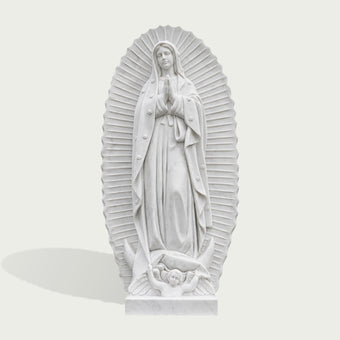 White marble Our Lady of Guadalupe statue featuring the Virgin Mary standing with hands clasped in prayer, surrounded by carved radiant rays and wearing a flowing star-decorated mantle, with a crescent moon and winged angel at the base.