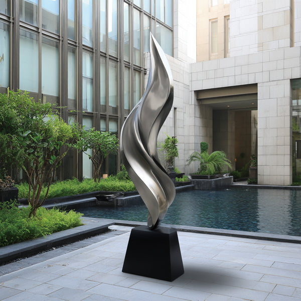 Abstract Stainless Steel sculpture in front of a modern building with a pool