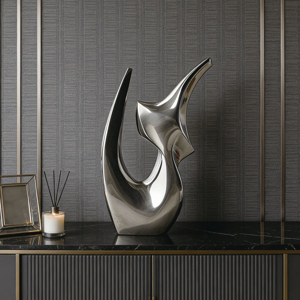 Silver abstract stainless steel sculpture on a black marble surface with a textured wall background