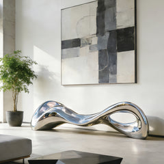 Modern Stainless Steel silver bench sculpture in a stylish living room with abstract art and plant.