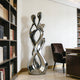 Abstract Embracing Lover Stainless Steel Sculpture in a room with bookshelves and a chair.