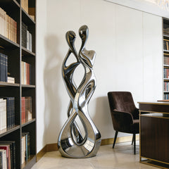 Abstract Embracing Lover Stainless Steel Sculpture in a room with bookshelves and a chair.