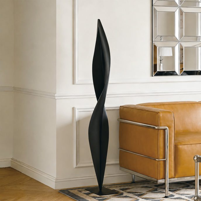 Abstract Slender Twisting Leaf Stainless Steel Sculpture and a brown leather sofa.